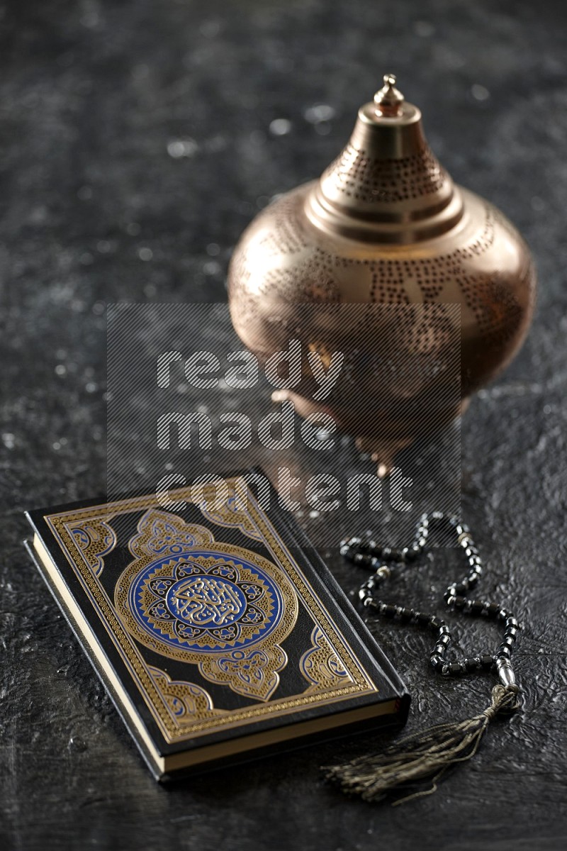 Quran with a prayer beads on textured black background