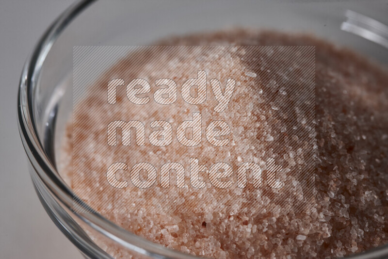 A glass bowl full of fine himalayan salt on white background