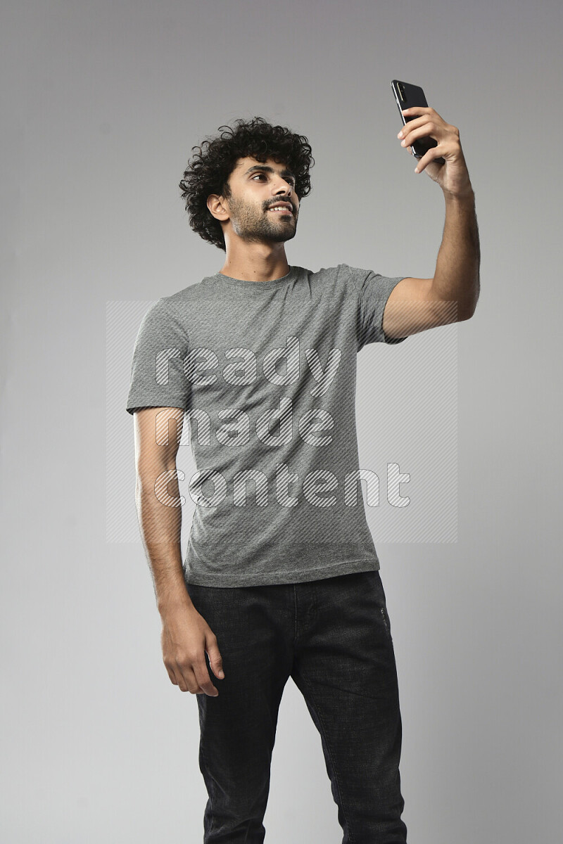 A man wearing casual standing and taking a selfie on white background