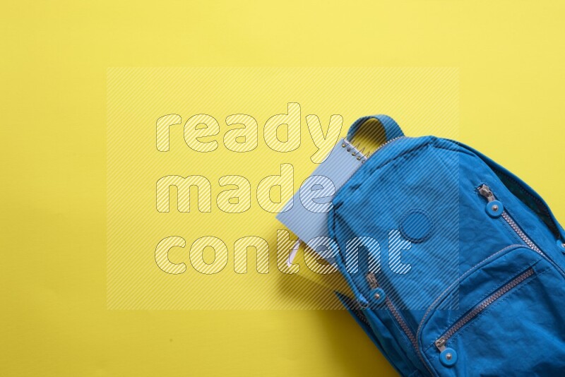A blue school bag placed on yellow background