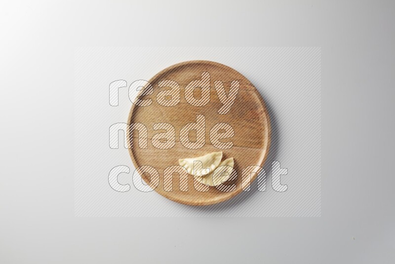 Two Sambosas on a wooden round plate on a white background
