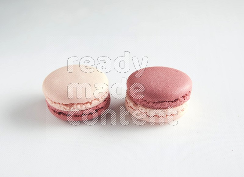 45º Shot of two Pink Litchi Raspberry macarons on white background