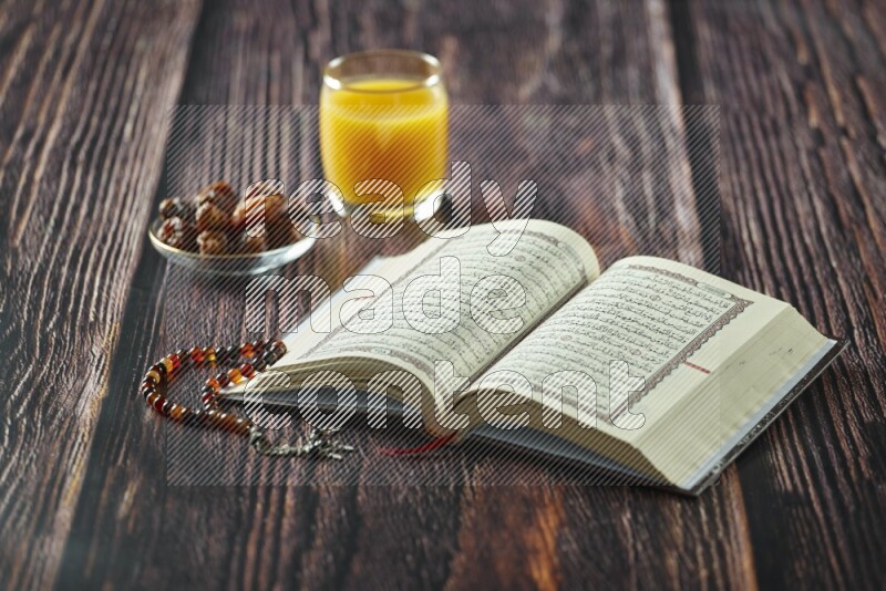 Quran with dates, prayer beads and different drinks all placed on wooden background