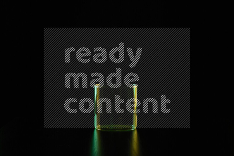 Glassware with rim light in green and yellow against black background