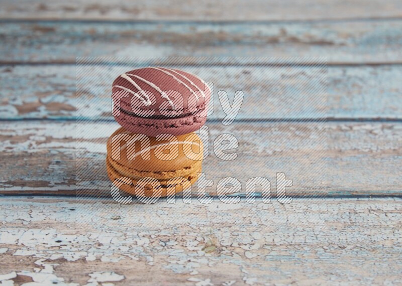 45º Shot of of two assorted Brown Irish Cream, and Red Poppy Flower macarons  on light blue background