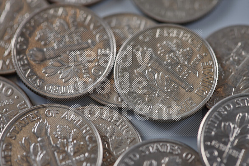 A close-up of scattered United States one dime coins on grey background