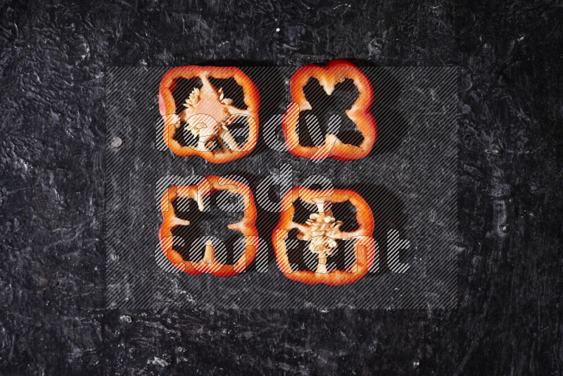 Red bell pepper slices on black background