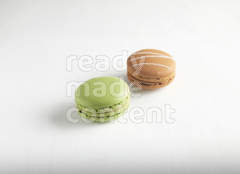 45º Shot of of two assorted Brown Irish Cream, and Green Pistachio macarons on white background