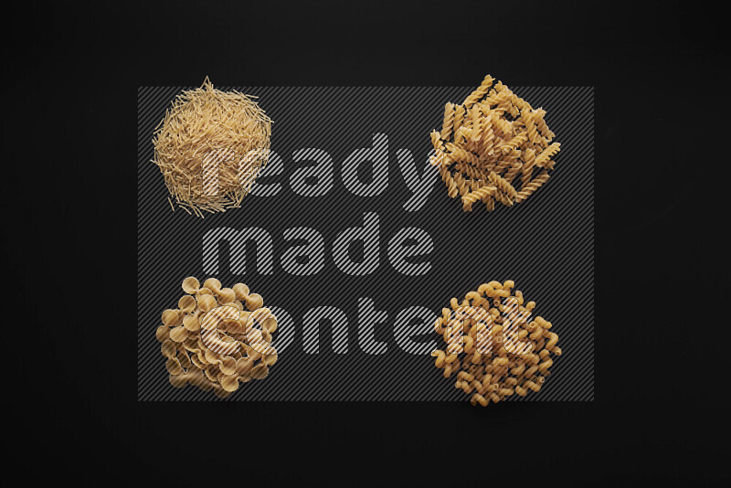 Different pasta types in bunches on black background