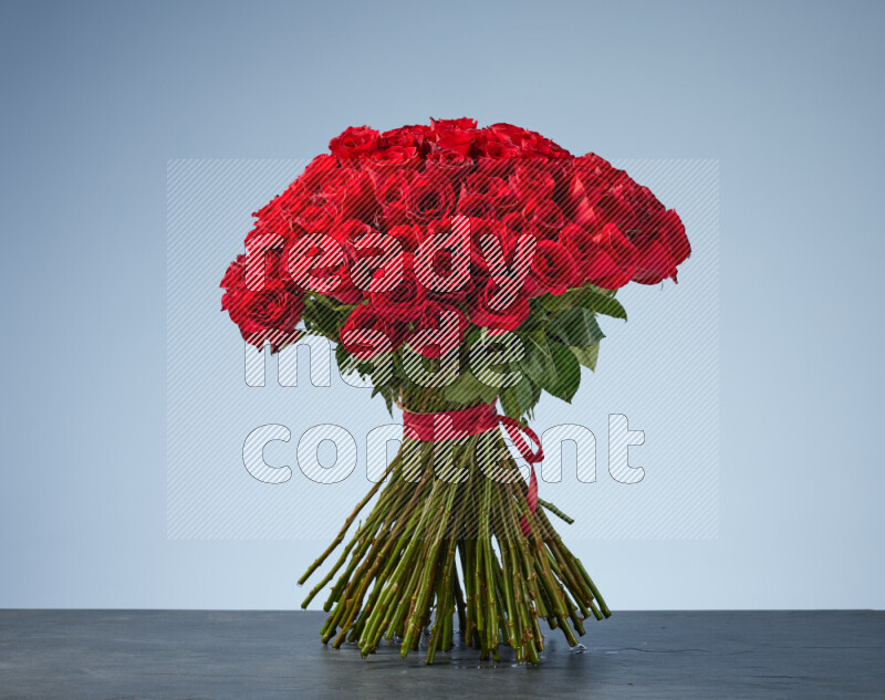 A luxurious bouquet of red roses tightly bound with a red ribbon on black marble background