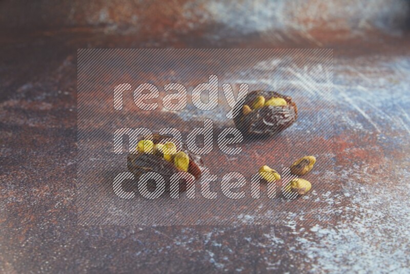 two pistachio stuffed madjoul dates on a rustic reddish background