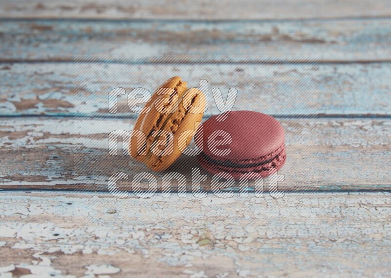 45º Shot of of two assorted Brown Irish Cream, and Red Cherry macarons  on light blue background