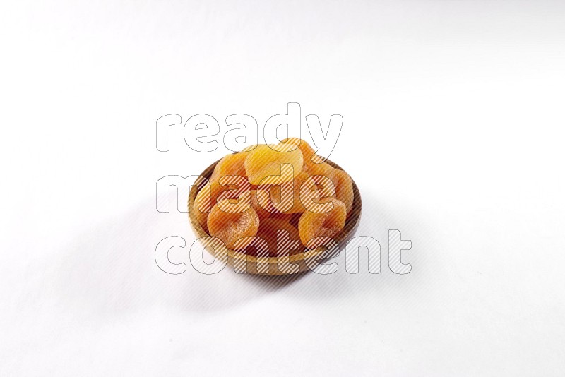 Dried apricots in a wooden bowl on white background