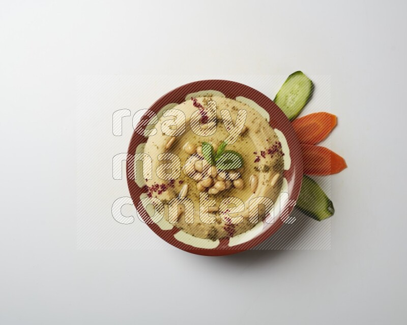 Hummus in a traditional plate garnished with zaatar & sumak on a white background