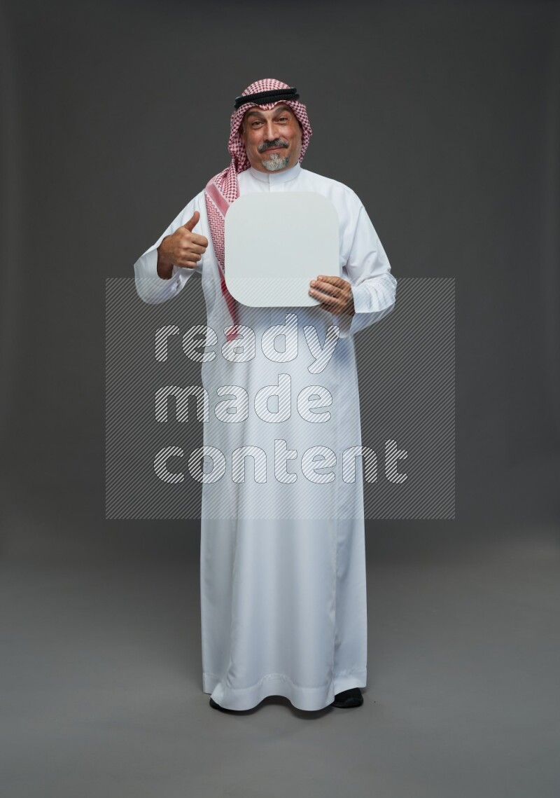 Saudi man with shomag Standing holding social media sing on gray background