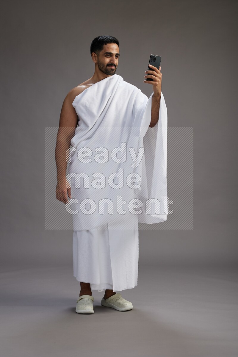 A man wearing Ehram Standing taking selfie on gray background