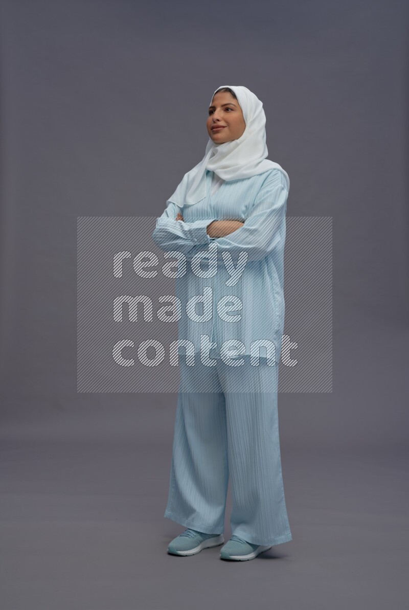Saudi woman wearing hijab clothes standing with crossed arms on gray background