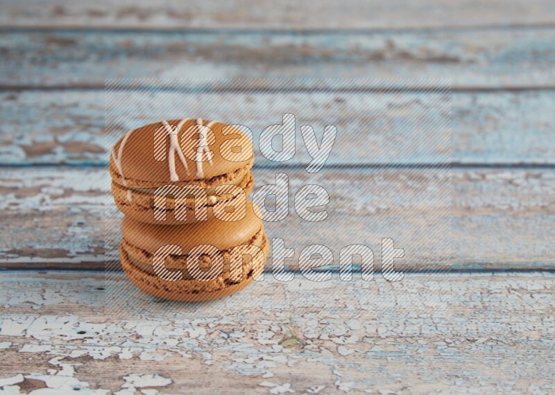 45º Shot of of two assorted Brown Irish Cream, and Brown Maple Taffy macarons  on light blue background