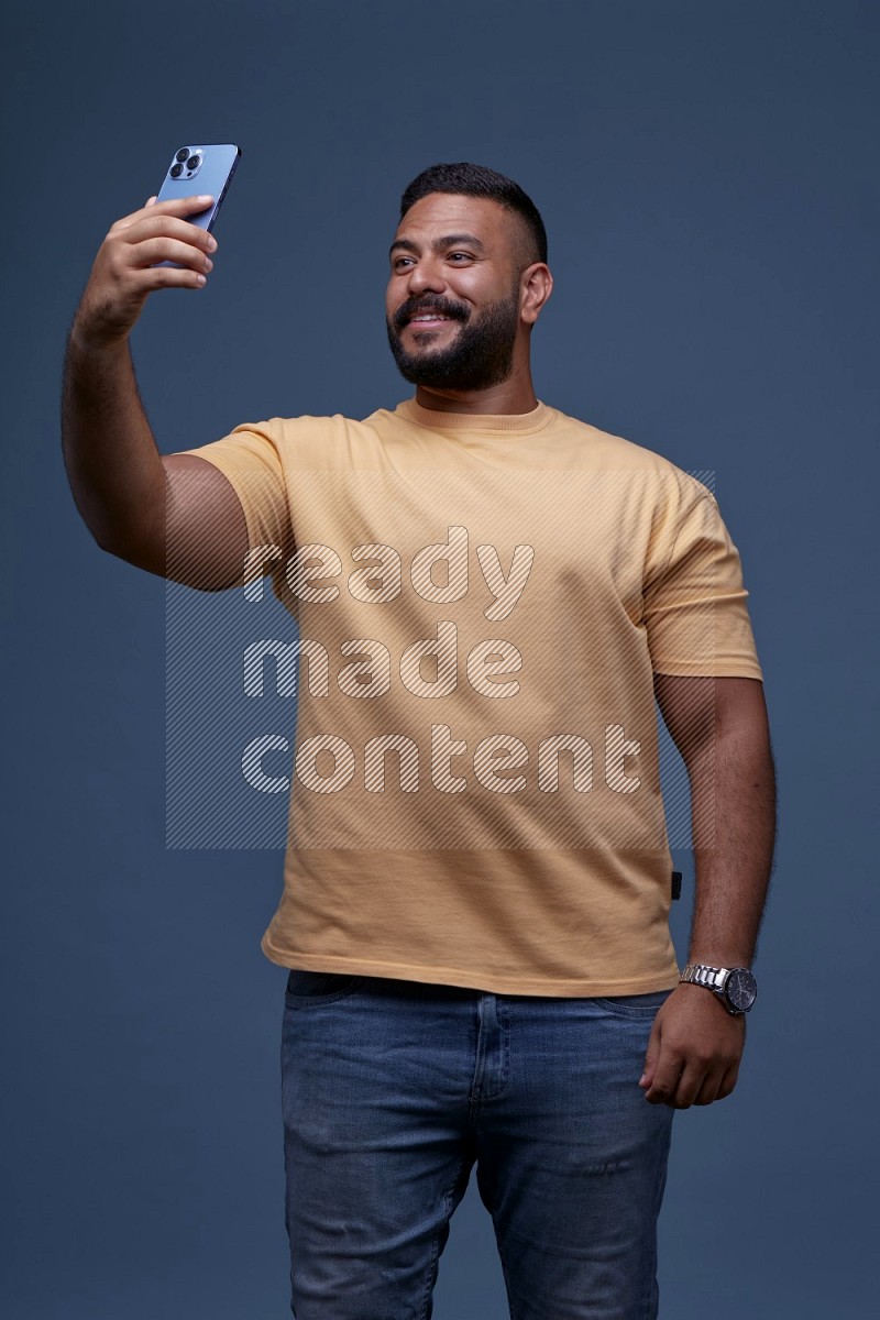 A man Taking A Selfie on Blue Background wearing Orange T-shirt