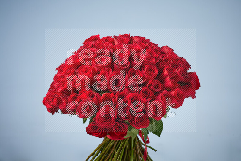 A luxurious bouquet of red roses tightly bound with a red ribbon on black marble background