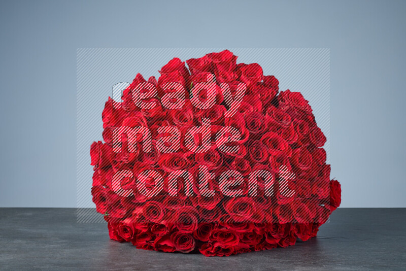 A sphere of vibrant red roses arranged tightly on black marble background
