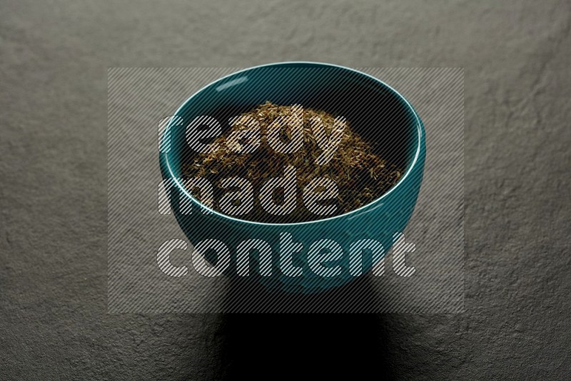 turquoise pottery round sauce bowl filled with herbs on grey textured countertop