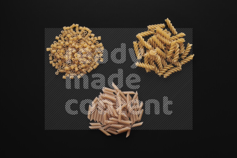 Different pasta types in bunches on black background