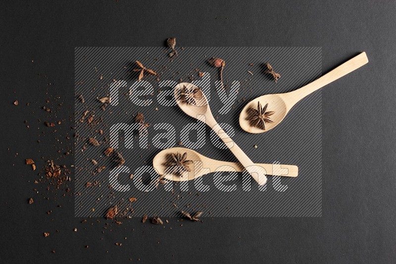 Star Anise in wooden spoons on black flooring