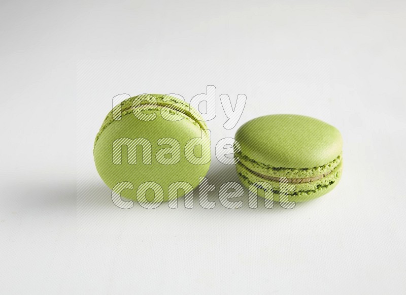 45º Shot of two Green Pistachio macarons on white background