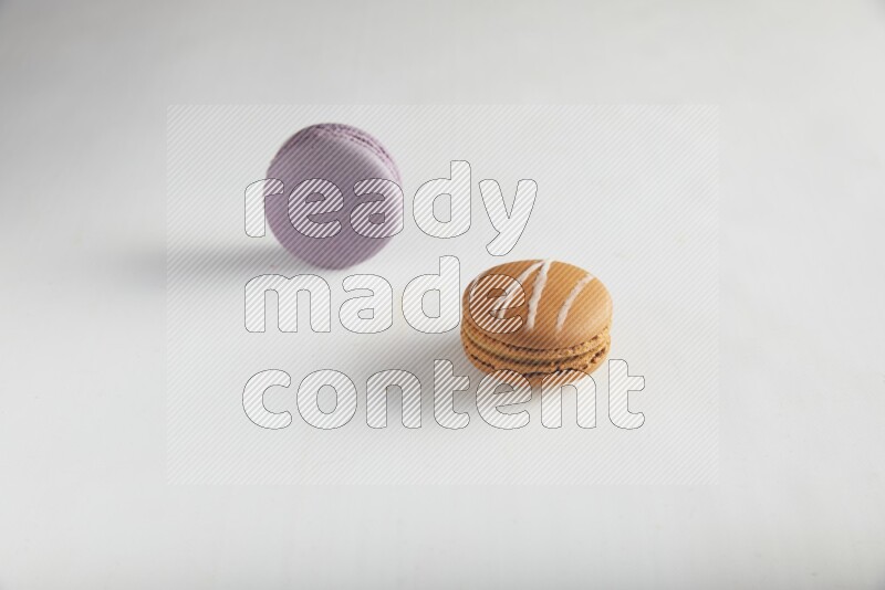 45º Shot of of two assorted Brown Irish Cream, and Purple Blueberry macarons on white background