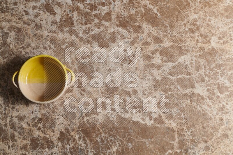 A multicolored pottery bowl on beige marble background