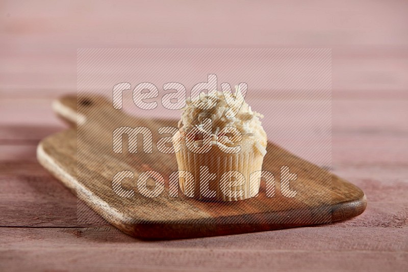 Vanilla mini cupcake topped with coconut on a wooden board