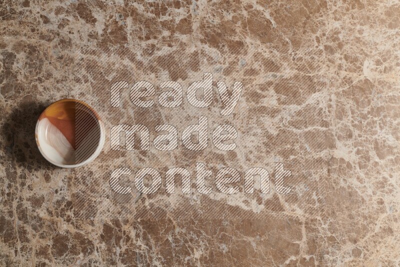 A multicolored pottery bowl on beige marble background