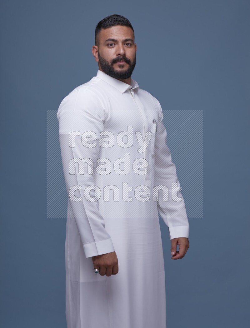 A man Posing in Blue Background wearing a Saudi Thob