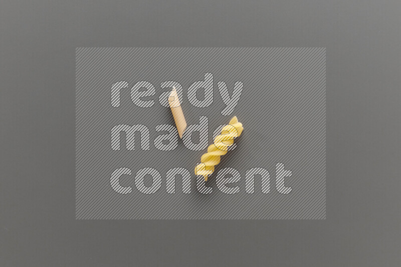 Mini penne pasta with other types of pasta on grey background