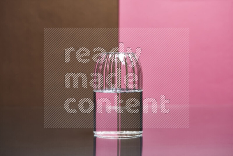 The image features a clear glassware filled with water, set against brown and pink background