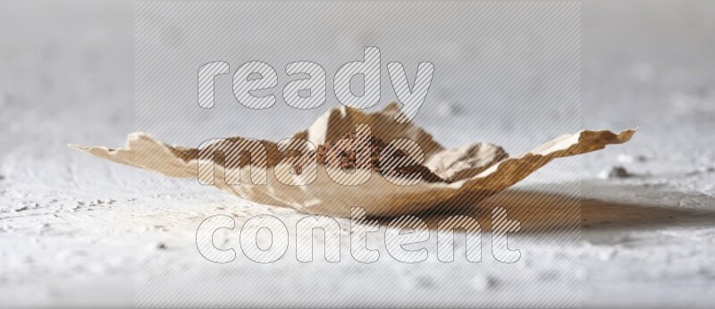 Cloves powder on crumpled piece of paper on a textured white flooring