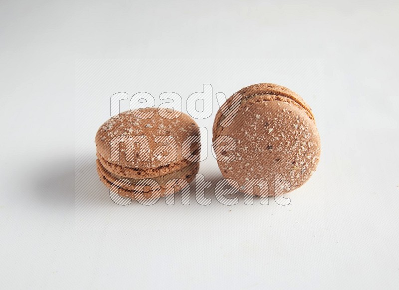 45º Shot of two Brown Hazelnuts macarons on white background