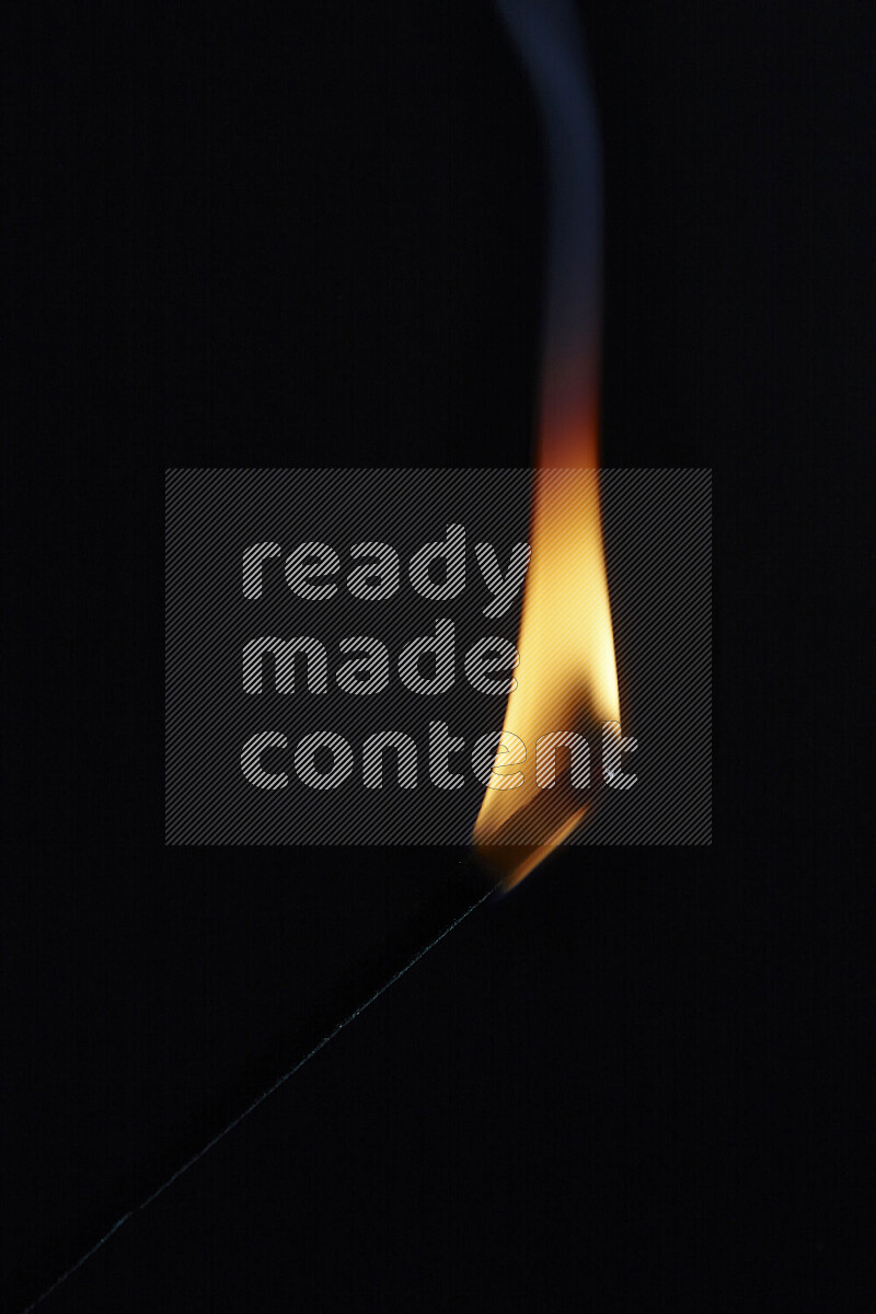 A burning incense stick isolated on dark backdrop