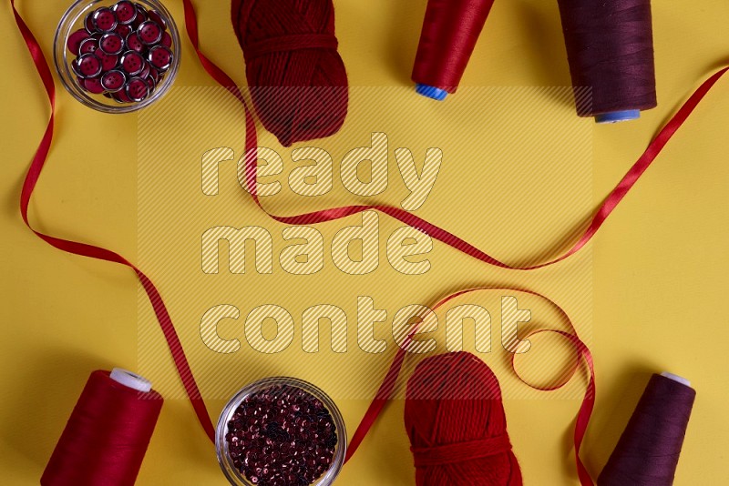 Red sewing supplies on yellow background