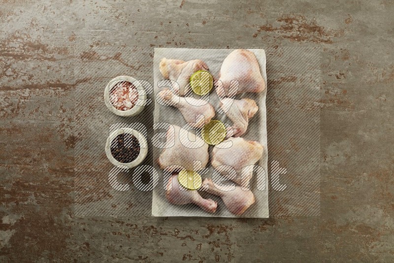 Mixed fresh chicken pieces on a parchment paper direct on a textured rustic background
