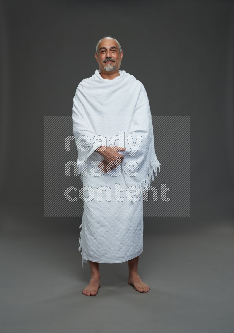 A man wearing Ehram Standing Interacting with the camera on gray background