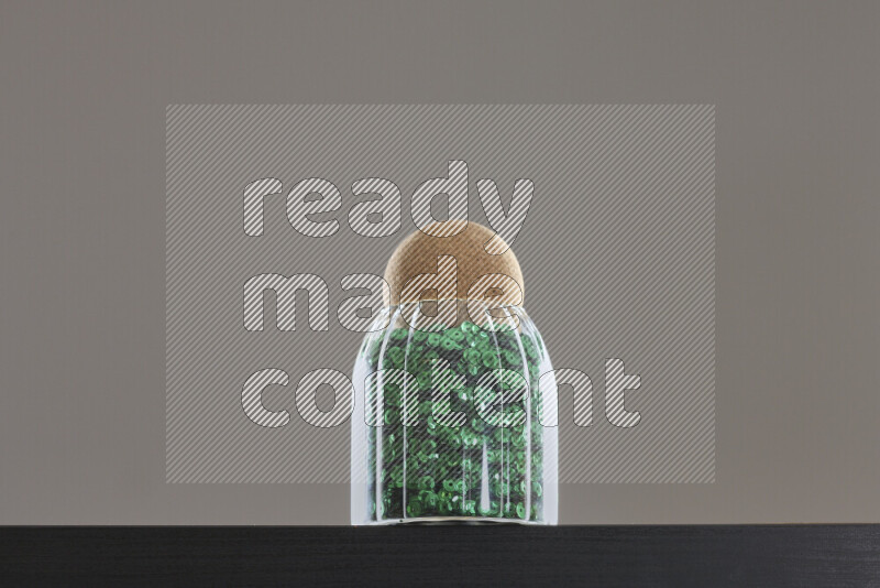 Sequins in a glass jar on black background