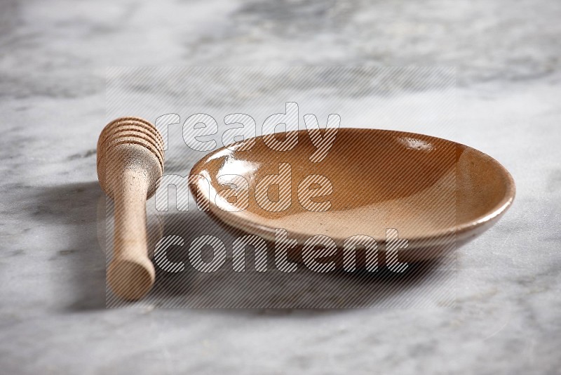 Multicolored Pottery Plate with wooden honey handle on the side with grey marble flooring, 15 degree angle