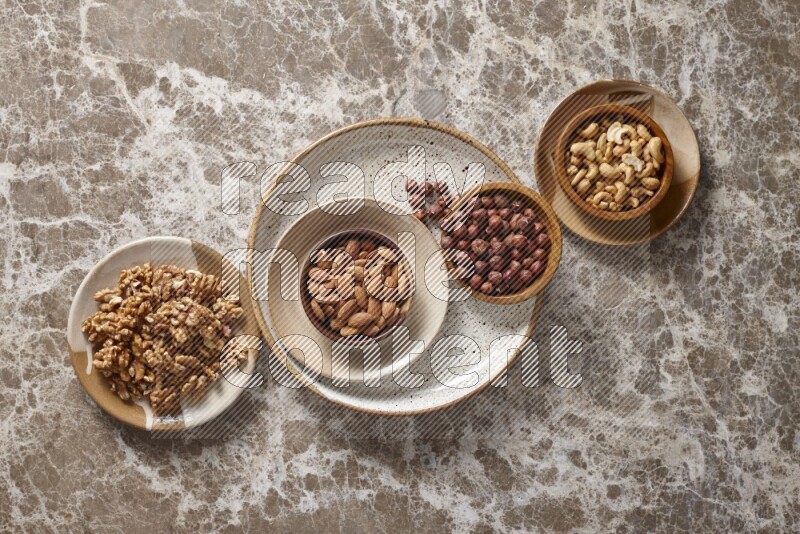 Nuts in pottery plates and wooden bowls in a light setup