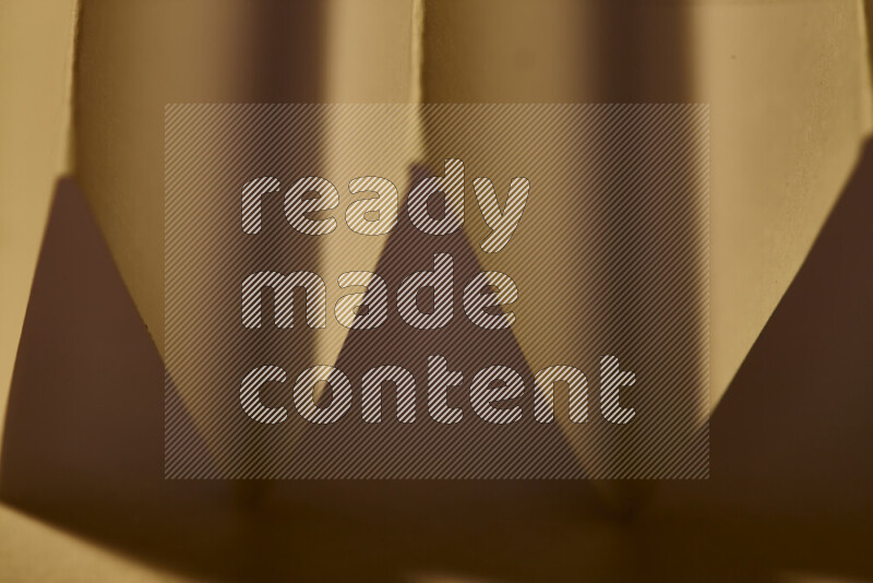 A close-up abstract image showing sharp geometric paper folds in warm gradients