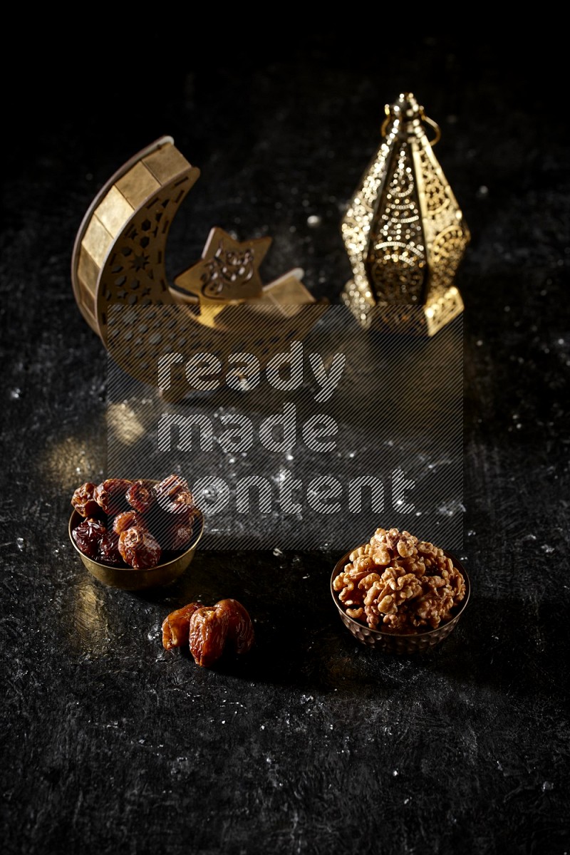 Dates in a metal bowl with walnuts beside golden lanterns in a dark setup