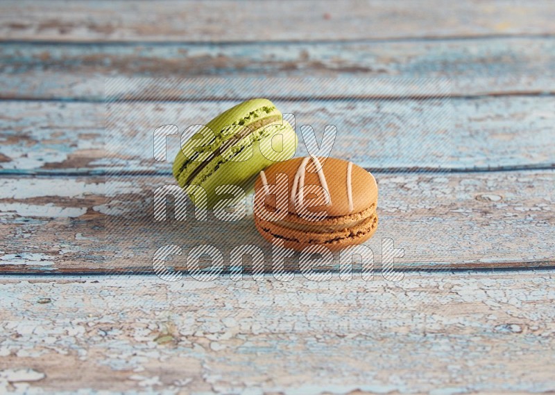 45º Shot of of two assorted Brown Irish Cream, and Green Pistachio macarons  on light blue background
