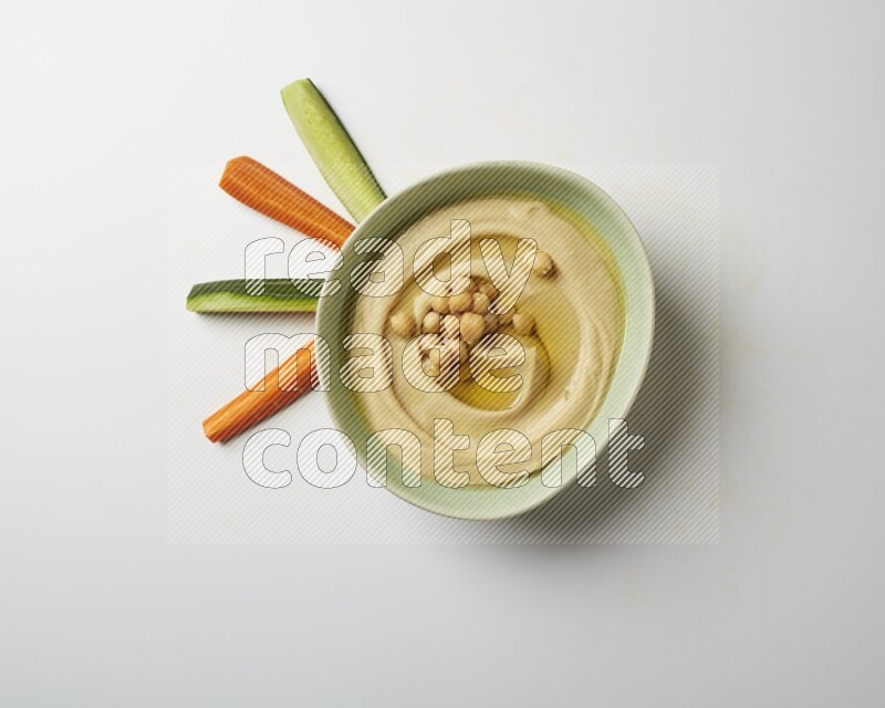 Hummus in a green plate garnished with roasted chickpeas  on a white background
