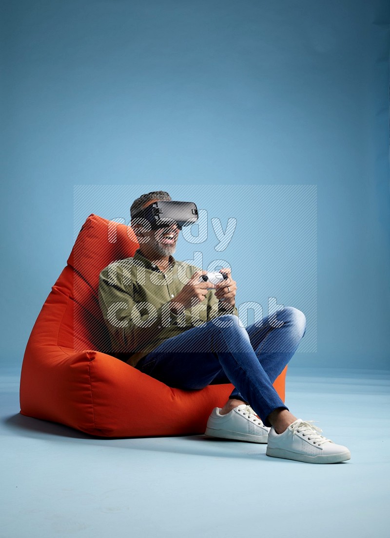 A man sitting on an orange beanbag and gaming with VR